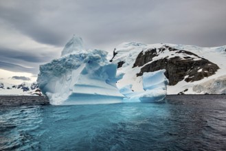 Large iceberg in the cold sea with snow-covered sky and dramatic atmosphere, icebergs in the