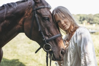 A serene image of a young girl in a white dress gently resting her head against a horse. They stand