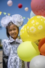 Happy schoolgirl with colourful balloons on the first day of school, Issyk-Kul region, Kyrgyzstan