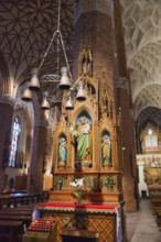 Gothic altar in a church with ornate figures of saints and candle lighting, St Jakobi Church,