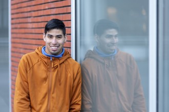 A person reflects calmly while leaning against a window at a mental health leisure center. Their