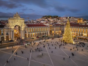 Twilight lights up Praca do Comercio, where a grand Christmas tree and festive displays fill the