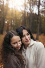 A warm embrace between a mother and daughter amidst the golden autumn foliage, capturing a tender