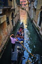 VENICE, ITALY, JUNE 27, 2018: Narrow canal between colorful old houses with gondola boat with