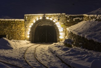Illuminated mouth hole from Markus-Röhling-Stolln visitor mine in the snow, historical origin to