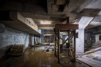 A dimly lit basement under construction, with structural beams and tools scattered about. The work