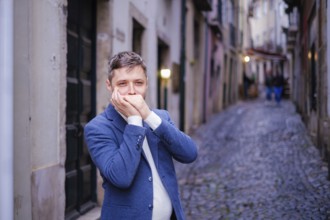Man musician in a blue blazer and white sweater playing blues on a harmonica with eyes closed,