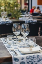 Set of glasses with white wine and plates placed on table with tablecloth on table