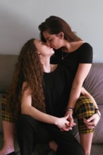 Two women, a female gay couple, share a loving kiss, intimately engaged in the moment. This warm