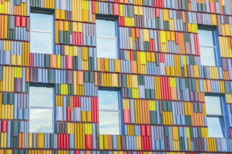 A detailed view of a building facade covered in a multitude of brightly colored panels arranged in