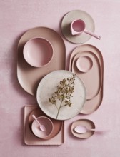 Top view of an artistic arrangement of ceramic crockery, featuring various shades of pink and