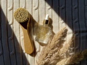A wooden brush and serum cosmetic bottle with golden serum rest on textured fabric, enhanced by