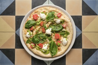 Top view of a delicious pizza with pesto, cherry tomatoes, basil and stracciatella cheese, served