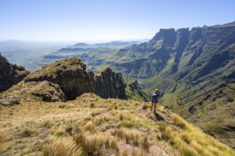Young hiker looking at the impressive mountains and cliffs of the Drakensberg Mountains, hiking