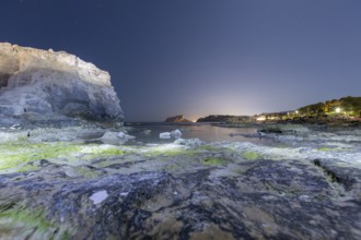 Tranquil Mediterranean shoreline on the Costa Blanca with rocky cliffs and calm sea under a starry