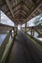 Long walkway of a wooden bridge over a wintry river course, Kälberbrücke, Enzklösterle, Calw
