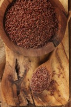 Natural, red rice, in a wooden bowl and spoon on a wooden surface in rustic style, top view