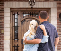 Happy Young Couple Facing Front Door of New House
