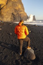 A tourist looking at the beautiful Reynisfjara Black Sand Beach in Iceland in winter