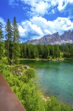 Emerald waters of lake carezza reflecting latemar mountain range in dolomites on a beautiful sunny