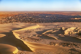 Desert town on the edge of the sand dunes, in the foreground extensive dune landscape, The dunes of