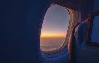 A breathtaking view of a sunrise from an airplane window, capturing the rich orange and blue hues