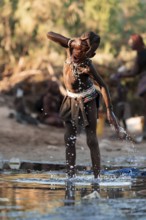Himba child washing with water on a river, traditional Himba, Kaokoveld, Kunene, Namibia