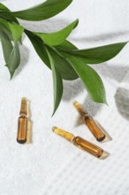 Close-up view of cosmetic ampoules with anti-aging serum, stylishly presented on a textured white