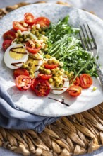 A vibrant keto lunch featuring boiled eggs, fresh rocket leaves, cherry tomatoes, canned green