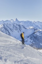 A snowboarder in a yellow jacket enjoys the snowy slopes with stunning mountain views. Bright