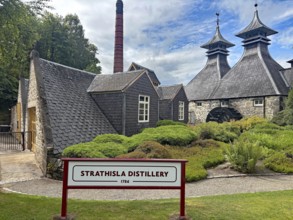 Historic Strathisla distillery with distinctive roofs and well-kept garden in rural surroundings,