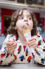 A young girl delights in a chocolate ice cream cone, savoring every bite on a sunny day in a