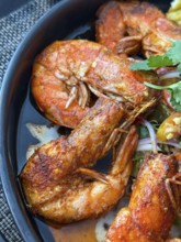 Close up of flavorful dish of seasoned fried shrimp served with a spicy dipping sauce in a Thai