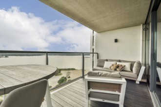 A stylish balcony featuring a cozy seating area overlooking a serene water view and bright sky,