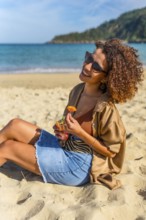 Arab modern young woman enjoying daydreaming on the beach sunbathing and eating tropical delicious