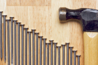 Hammer and Declining Graph of Nails Abstract on Wood Background