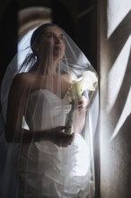 A bride in a stunning white gown stands gracefully inside an ancient villa in Treia, Macerata. The