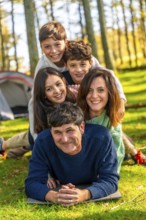 Caucasian family having fun together lying on the forest one on top of each other next to camping