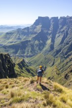 Young hiker looking at the impressive mountains and cliffs of the Drakensberg Mountains, hiking