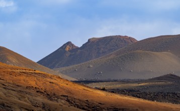 Scenic view of Timanfaya National Park's dramatic volcanic landscape with sunlit hills and rugged