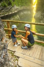Mother and child wearing helmets, holding hands, enjoying the scenic beauty of vintgar gorge near