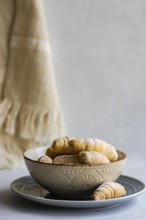 A decorative bowl filled with freshly baked homemade pastries, placed on a plate. The pastries are