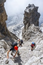 Three hikers climb the Cima falconer mountain peak, Brenta Mountains, Brenta, Brenta-Adamello