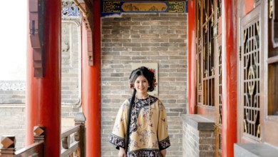 Woman dressed in traditional Qing dynasty clothing stands in Pingyao, China, looking at the camera.