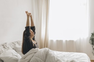 A woman stretches in bed, bathed in soft morning light, symbolizing a fresh start. The peaceful