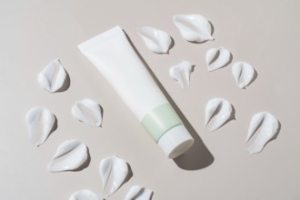 An elegant cosmetics container with a minimalist design appears next to artistic cream stains on a