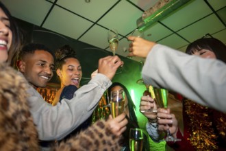 Group of happy multiracial friends enjoying a lively party in a nightclub, smiling and toasting