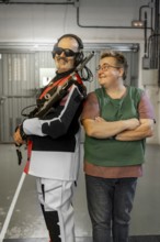 A blind shooting champion stands confidently with a supportive partner at an indoor shooting range.