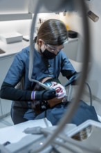 Dentist using specialized equipment for teeth whitening treatment on a patient in a modern dental