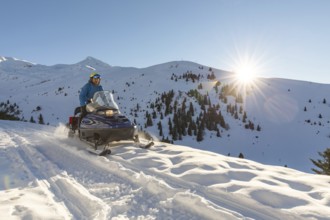 A snowmobiler rides through the picturesque snowy mountains, enjoying the stunning winter landscape